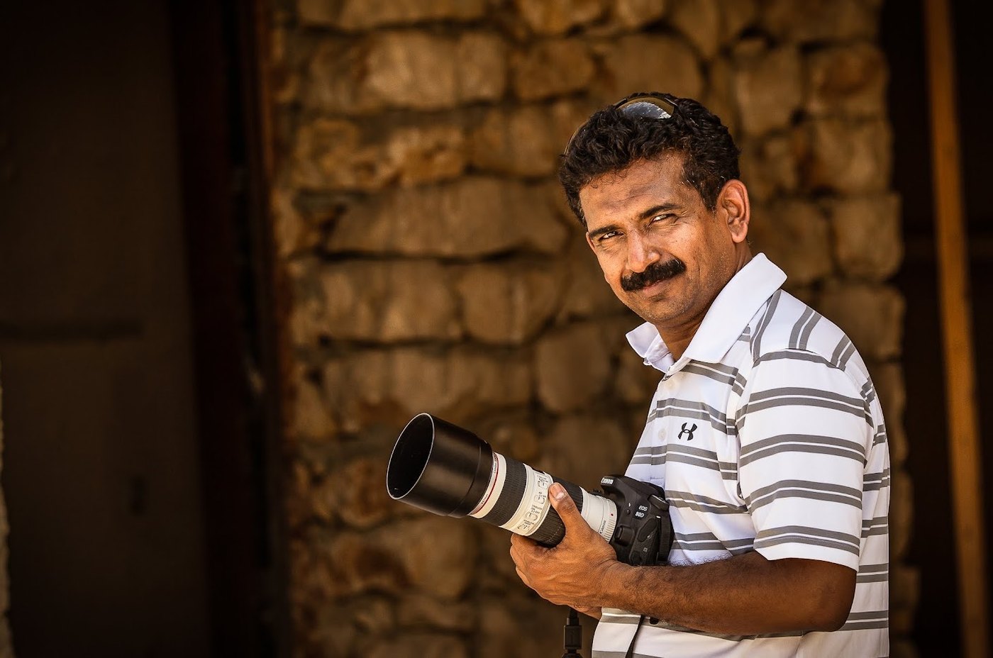 Jaison Chacko with his camera outside a stone building