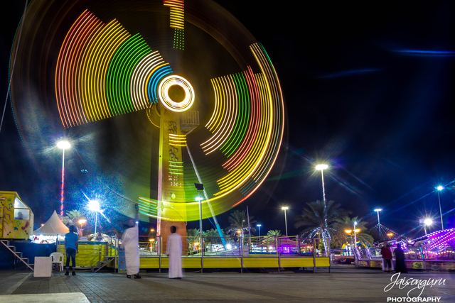 Fairground wheel spinning into a blur of colour at night