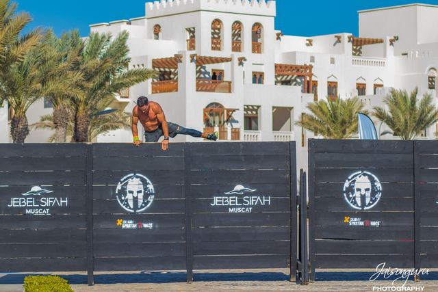 Competitor climbing the wall on an obstacle course