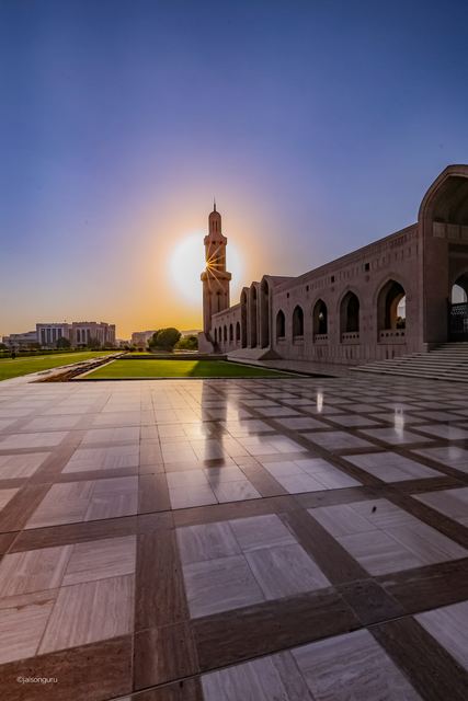 Minaret of the Sultan Qaboos Grand Mosque with the sun flaring behind it