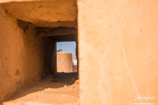 Looking out through a fort's stone embrasure to the tower beyond