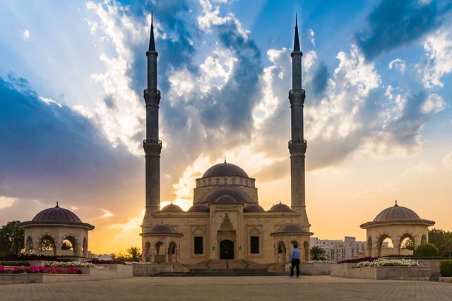 Twin minarets and dome of a mosque under towering afternoon cloud