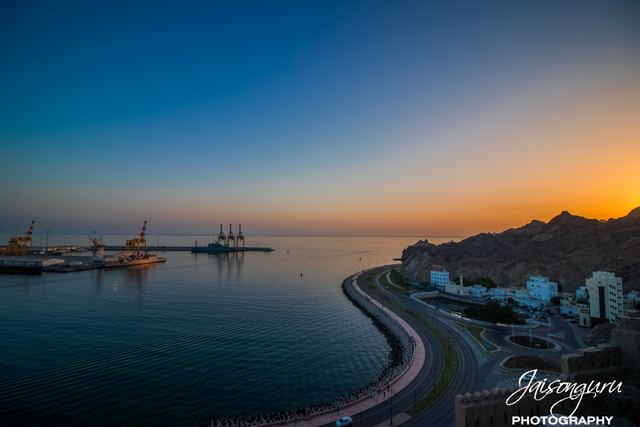 Blue hour over the bay with corniche lights curving into the distance