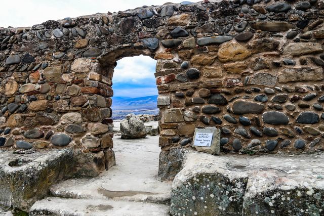 Stone archway in a ruined settlement framing the valley beyond