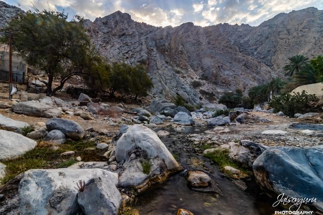Boulder-strewn wadi bed winding between dry mountains