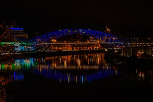 Illuminated bridge mirrored in the harbour at night