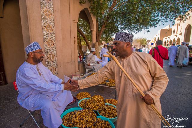 Two traders shaking hands over baskets of dates