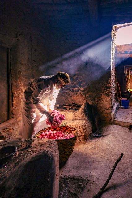 Rose water distillation over a wood fire, light falling through the doorway