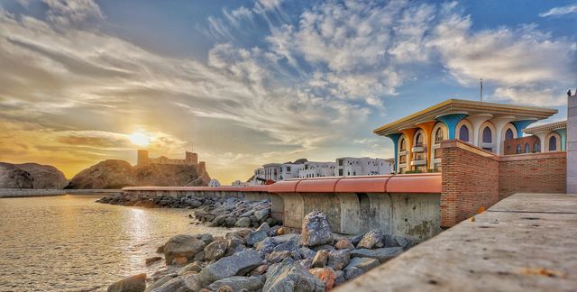 Sunrise over a rocky corniche with an old fort on the headland