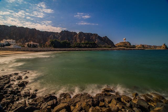 Waves breaking over dark rocks with green shallows beyond