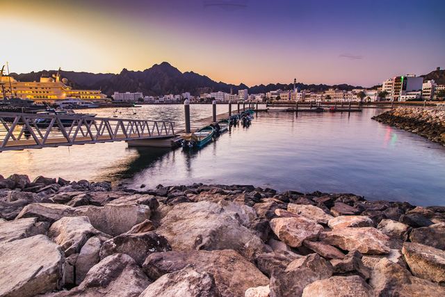 Long exposure of a pier at dusk with mountains behind the harbour